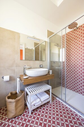 A modern bathroom with a large white sink, a mirror, a shower, and patterned floor tiles. - Napoli Bellavista Apartment (Naples)