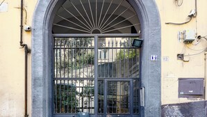 Suuri, kaareva metalliportti, jonka yläpuolella on koristeellinen puolikuuluva ikkuna, ja joka on sijoitettu mukulakivikadulle.