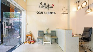 The interior of COZI 5 HOTEL with a reception desk, two chairs, a small table, and a decorative plant. - Collection O Cozy 5 Hotel - Near SECC (Ho Chi Minh City)