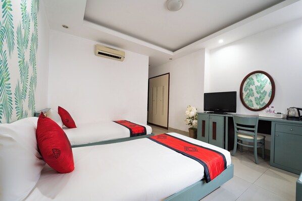 A hotel room with two beds, a desk, a chair, a television, and a decorative mirror.