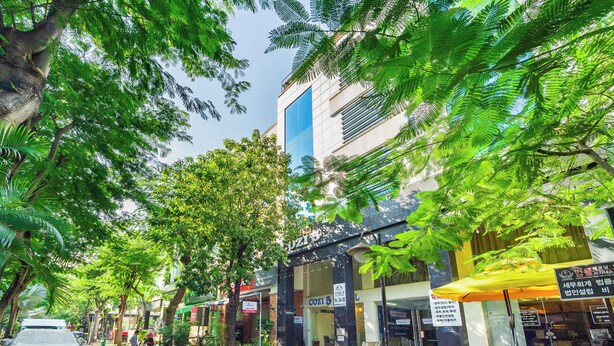 A street lined with trees and buildings, including a visible storefront with a sign. - Collection O Cozy 5 Hotel - Near SECC (Ho Chi Minh City)