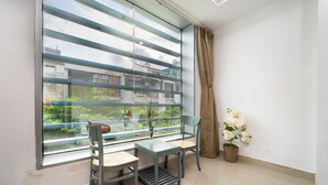 A room with a large window, a small table, two chairs, and a potted plant. - Collection O Cozy 5 Hotel - Near SECC (Ho Chi Minh City)