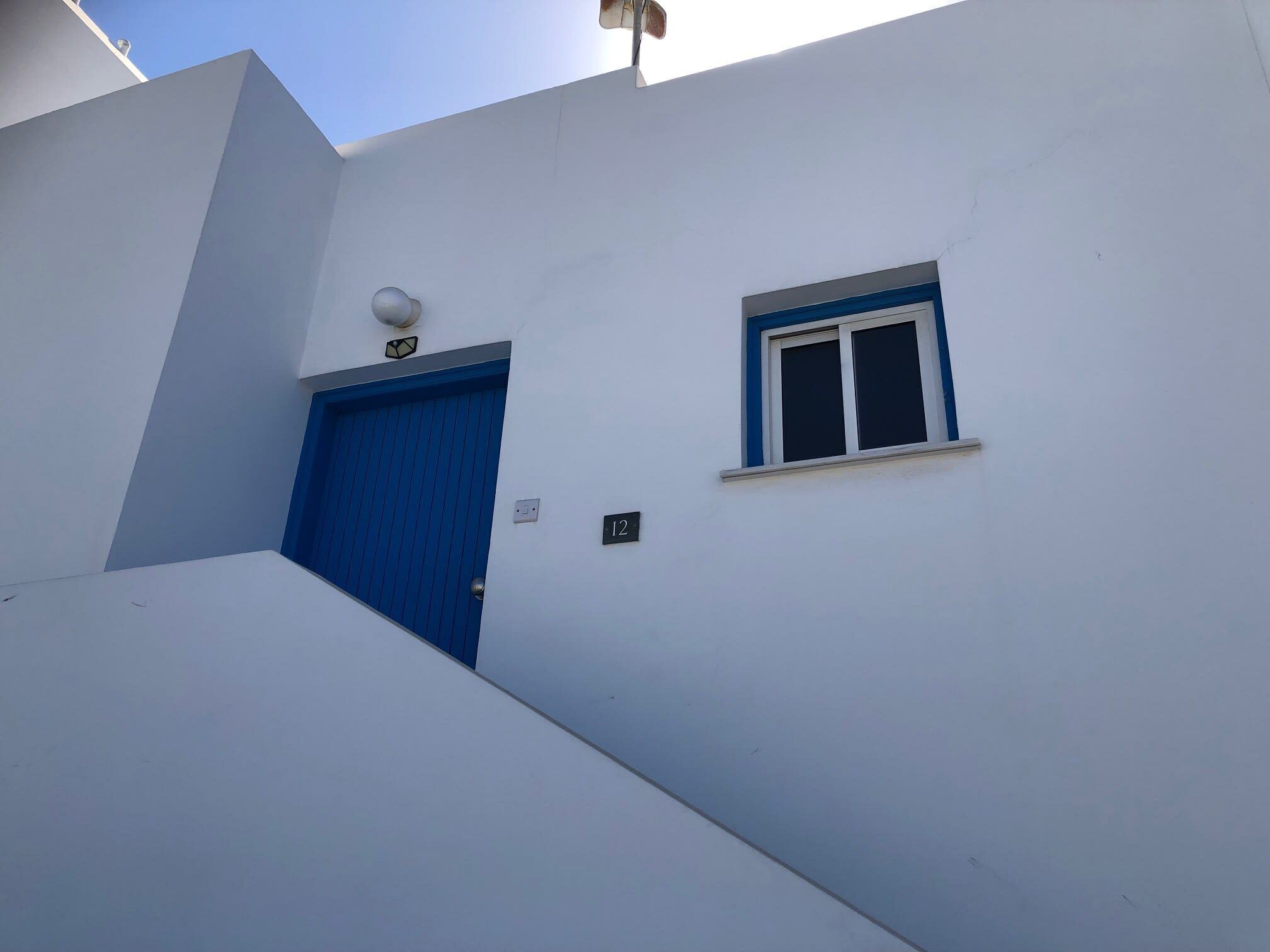 Ein weißes Gebäude mit einer blauen Tür und einem kleinen Fenster.