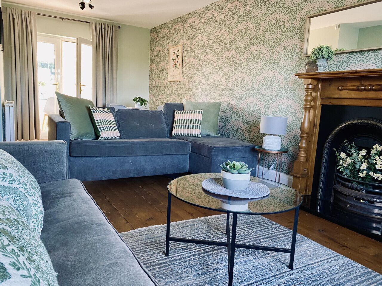 A living room with a blue sofa, a round coffee table with a plant, and a fireplace.