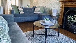A living room with a blue sofa, a round coffee table with a plant, and a fireplace.