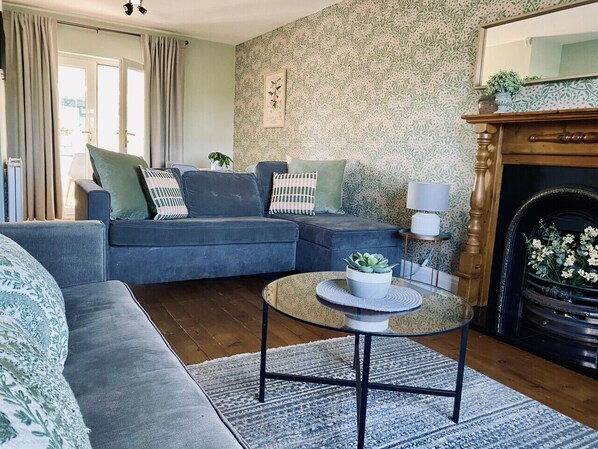 A living room with a blue sofa, a round coffee table with a plant, and a fireplace.