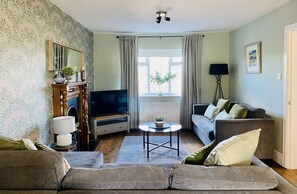 A living room with a sofa set, a television, a coffee table, and a lamp.