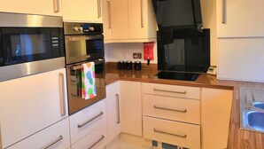 A modern kitchen with stainless steel appliances, wooden cabinets, and a built-in oven.