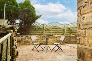 An outdoor patio with stone walls, a wooden fence, and two folding chairs.