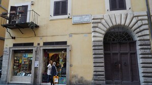 En byggnad med en entré som har en valvformad stenöppning, en skylt med texten ”VIA DEL GOVERNO VECCHIO” och ett skyltfönster med böcker och en skylt som visar att det är en pub med livemusik.