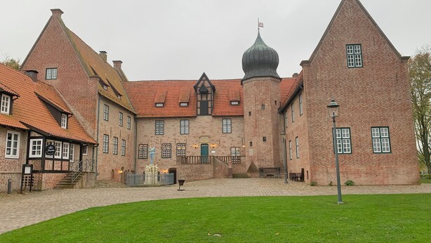 A historic building with a central tower, multiple windows, and a flag.