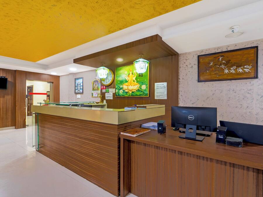 A reception desk with a clock, a computer, and a framed artwork on the wall.