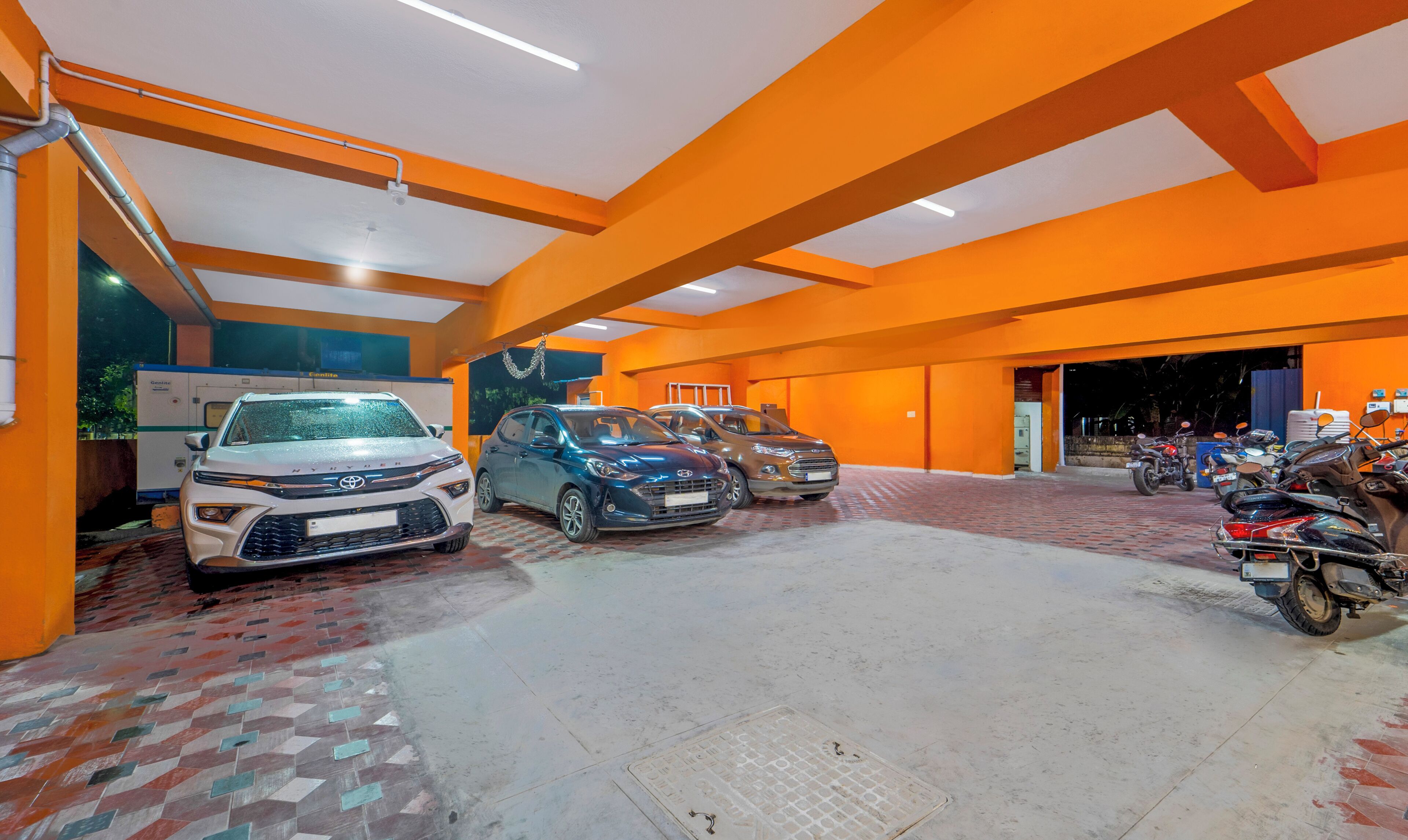 Ett parkeringsgarage med flera bilar och motorcyklar, med orangefärgade väggar och ett klinkergolv.
