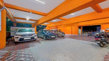 Ett parkeringsgarage med flera bilar och motorcyklar, med orangefärgade väggar och ett klinkergolv.