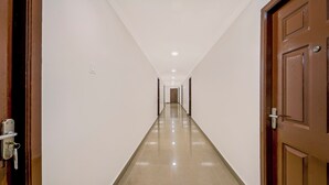 A long, narrow hallway with a shiny floor and white walls. - NVR RESIDENCY (Chennai)