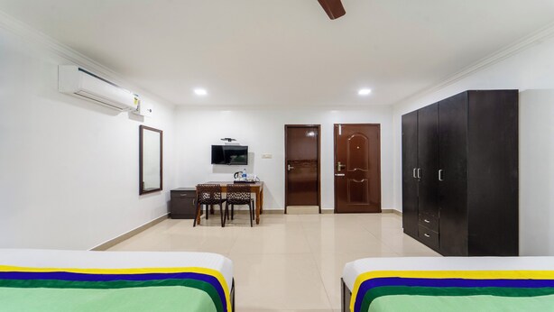 Habitación de hotel con dos camas, un escritorio con silla, televisión y armario.