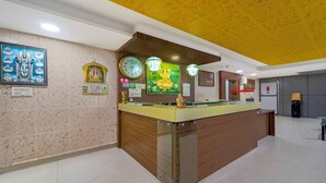 A reception area with a wooden counter, wall-mounted clocks, and religious artwork. - NVR RESIDENCY (Chennai)