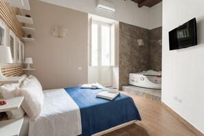 A hotel room with a bed, a TV, a massage chair, and a window with a view of the outside. - Casa Papaccio Luxury (NAPOLI)