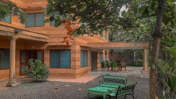 Une cour avec un bâtiment, deux bancs verts et une pergola.