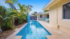 A swimming pool with lounge chairs and palm trees. - Beach Walk Villa with Waterfall Pool LBTS (Lauderdale-by-the-Sea)