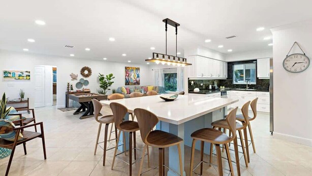 A modern kitchen with a central island, bar stools, and a hanging light fixture. - Beach Walk Villa with Waterfall Pool LBTS (Lauderdale-by-the-Sea)