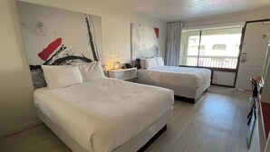 Una habitación de hotel con dos camas, un escritorio con lámpara y obras de arte en las paredes.