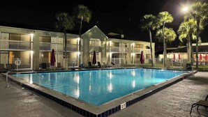 Un hotel con piscina, varios balcones y palmeras.