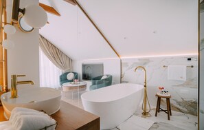 Enjoy a relaxing soak in the bathtub, accompanied by a large vanity and round mirror.