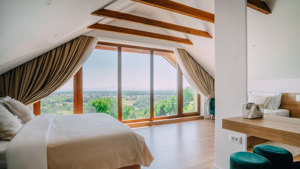 A bedroom with a large window, wooden beams, a bed, a desk, and a chair. - Nice home in Vukanovec with sauna (Vukanovec)