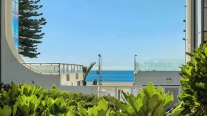 Un edificio moderno con fachada de vidrio curva que da a una playa.