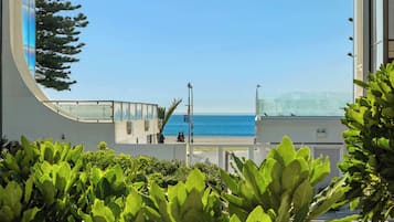 Ein modernes Gebäude mit einer gewölbten Glasfassade und Blick auf einen Strand.