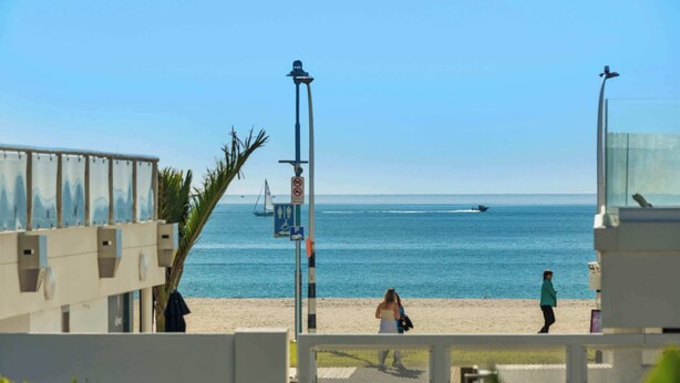 Vista de una playa con cielo despejado, una torre de salvavidas y arena.