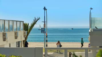 Une vue sur la plage, avec un ciel dégagé, une tour de surveillance des sauveteurs et une plage de sable.