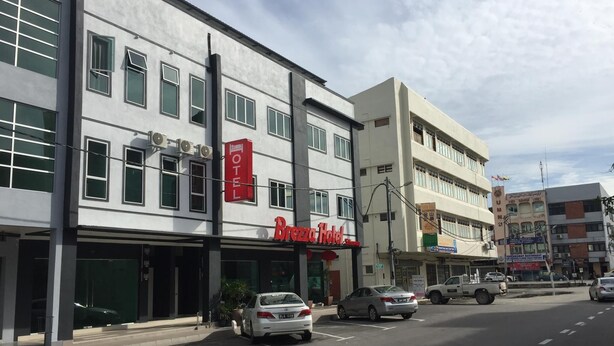 Un hôtel reconnaissable à son grand panneau rouge, à ses nombreuses fenêtres et à son parking rempli de voitures.