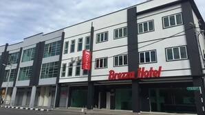 L’hôtel Brezza se distingue par sa façade moderne, ses nombreuses fenêtres et son grand panneau rouge.