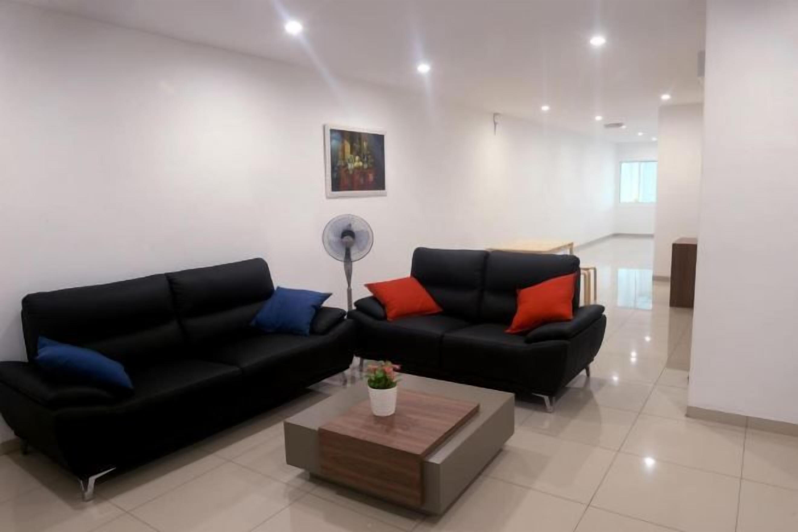 A modern living room with two black sofas, a wooden coffee table, and a floor lamp.