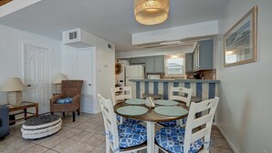 A dining area with a round table, chairs, and a hanging light fixture. - Canal Views & Pool | 2 Min to Beach | Fishing Pier (Corpus Christi)