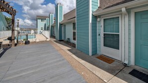 A row of turquoise buildings with a wooden deck in front, a pool, and a gazebo. - Canal Views & Pool | 2 Min to Beach | Fishing Pier (Corpus Christi)