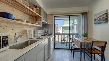 Cozinha moderna com uma grande janela, prateleiras de madeira e um espaço de refeições com mesa e cadeiras.