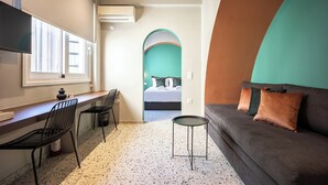 Una habitación de hotel moderna con kitchenette, sofá, cama y televisor.