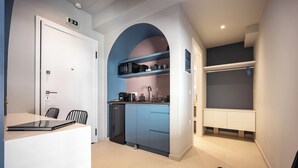Una cocina compacta con lavavajillas integrado, cafetera y microondas. Hay un pequeño rincón de descanso con una mesa y sillas.