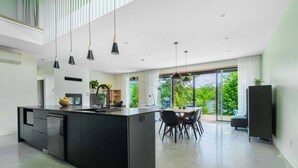 Una cocina moderna con una isla central, muebles negros e iluminación colgante.