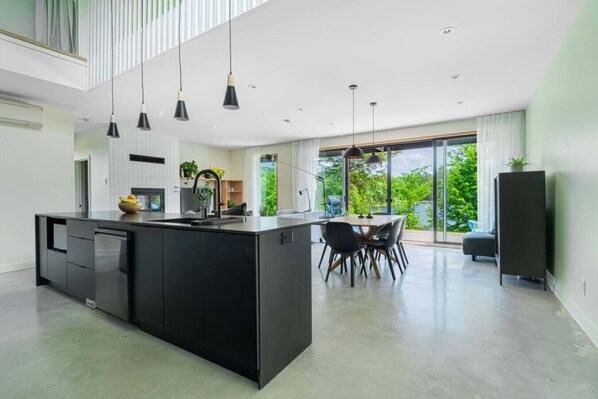 A modern kitchen with a central island, black cabinetry, and pendant lighting. - Luxurious Chalet Aube - Waterfront, Spa, Fireplace (Grenville-sur-la-rouge)