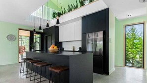 Una cocina moderna con una isla central, taburetes de bar y vistas al exterior.