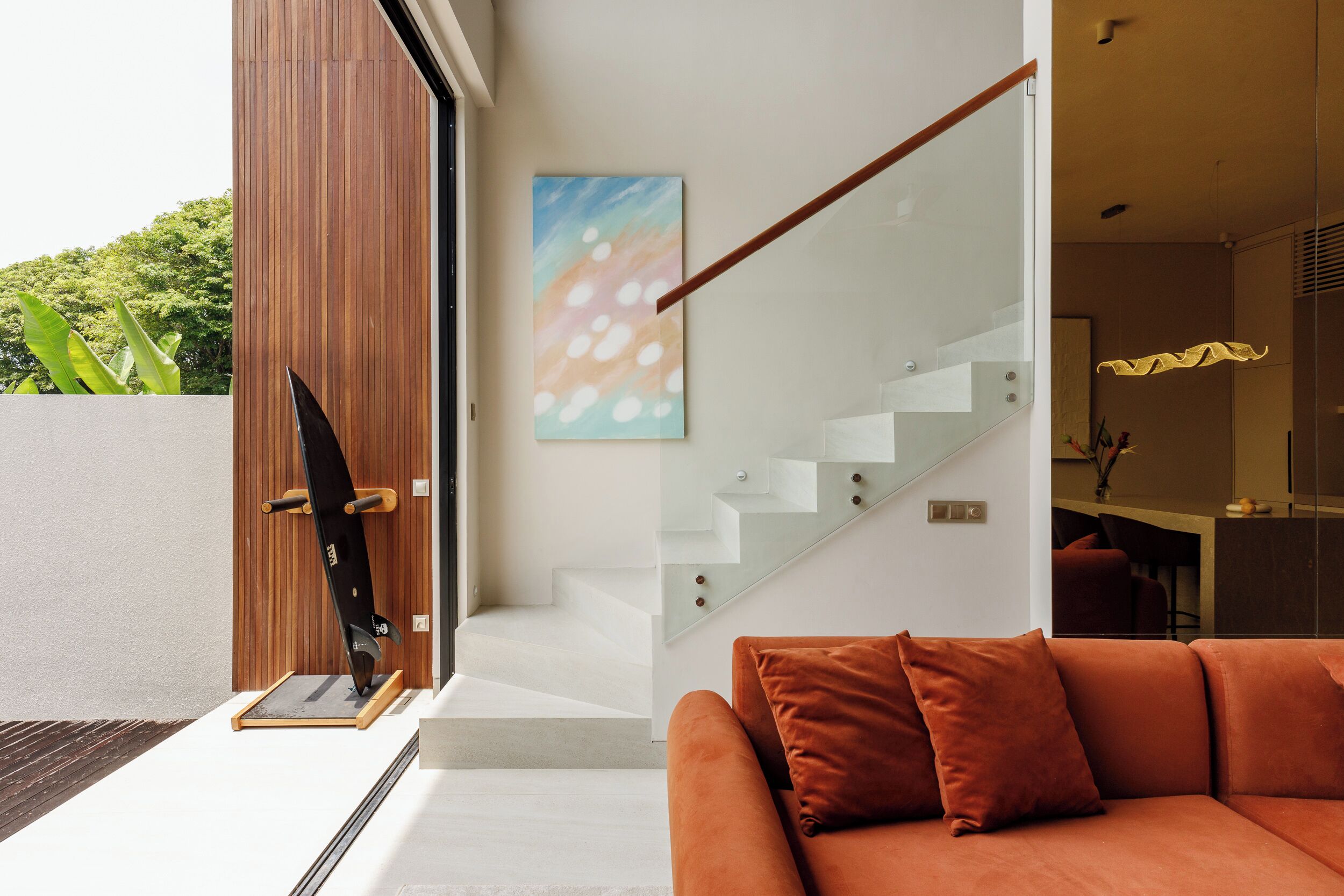 A modern interior with a staircase, a sofa, and a skateboard.