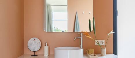 Een moderne badkamer met een witte wastafel, houten kastjes en een grote spiegel.