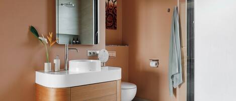 A modern bathroom with a curved vanity, a toilet, and a glass shower enclosure.