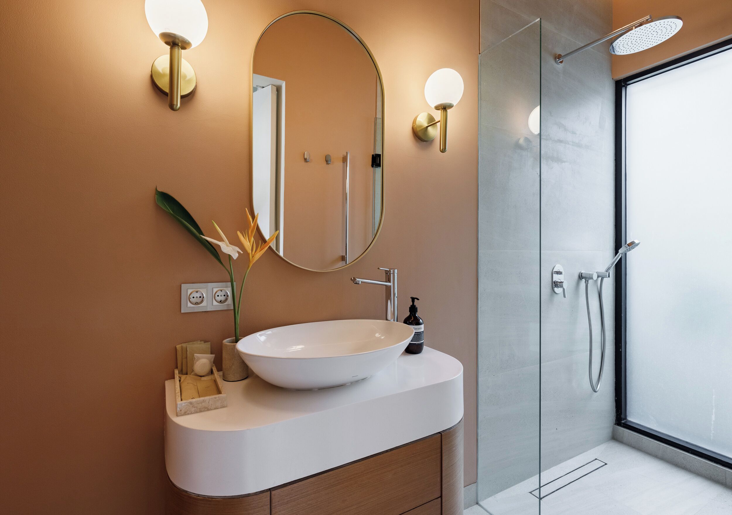 A modern bathroom with a large oval sink, a mirror, and a glass-enclosed shower.