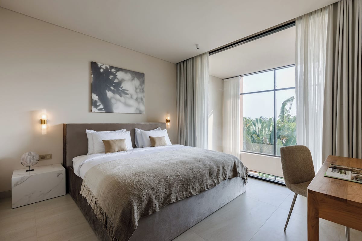 Ein modernes Hotelzimmer mit einem großen Bett, einem Schreibtisch und Blick auf Grün.