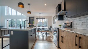 A modern kitchen with a central island, pendant lighting, and a view of the outdoors. - Scandinavian chalet | SPA and Pool Table | Le 70 (Lanaudière)